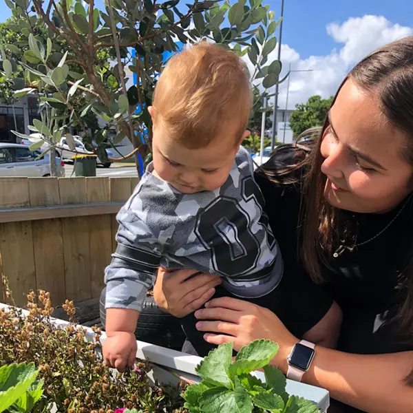 friendly teacher helping infant touch plants