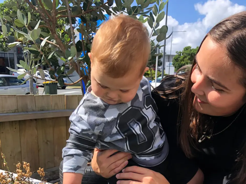 friendly teacher helping infant touch plants