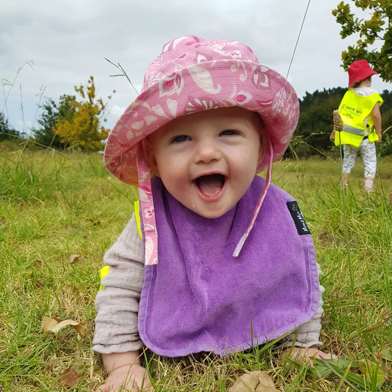 happy little girl on grass with pink sunhat