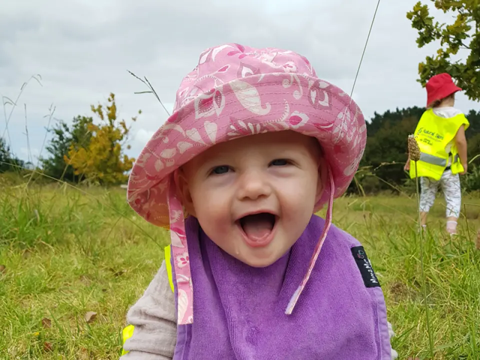happy little girl on grass with pink sunhat