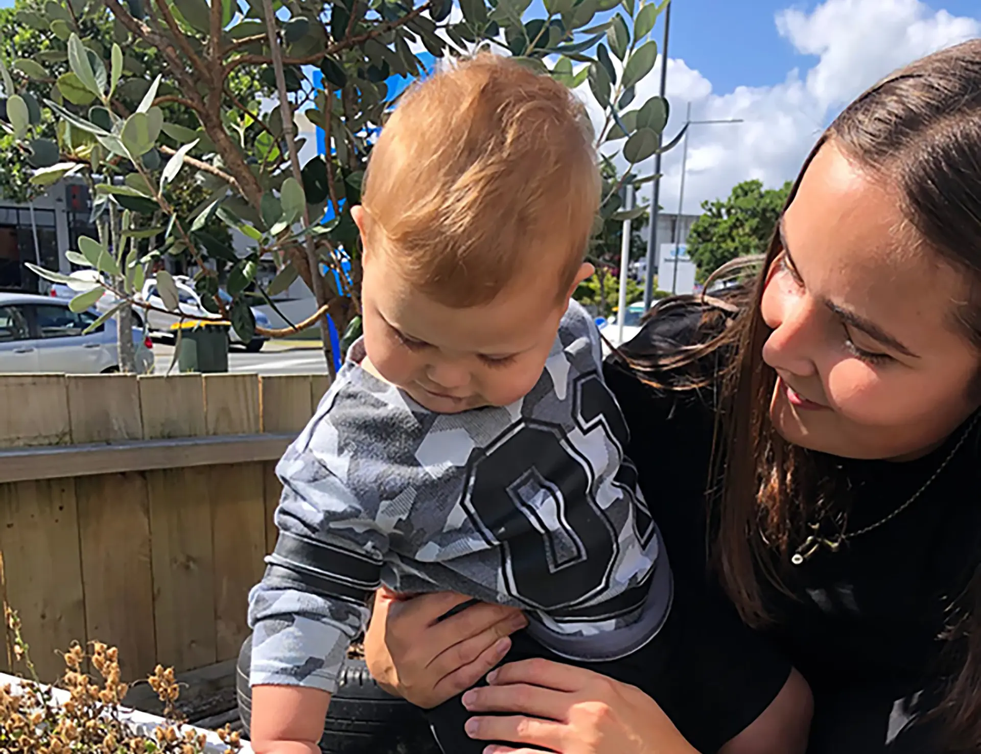friendly teacher helping infant touch plants landscape