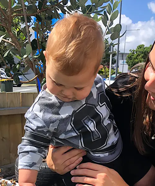 friendly teacher helping infant touch plants landscape
