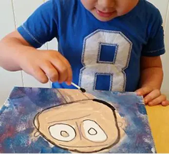 boy drawing a face using paint