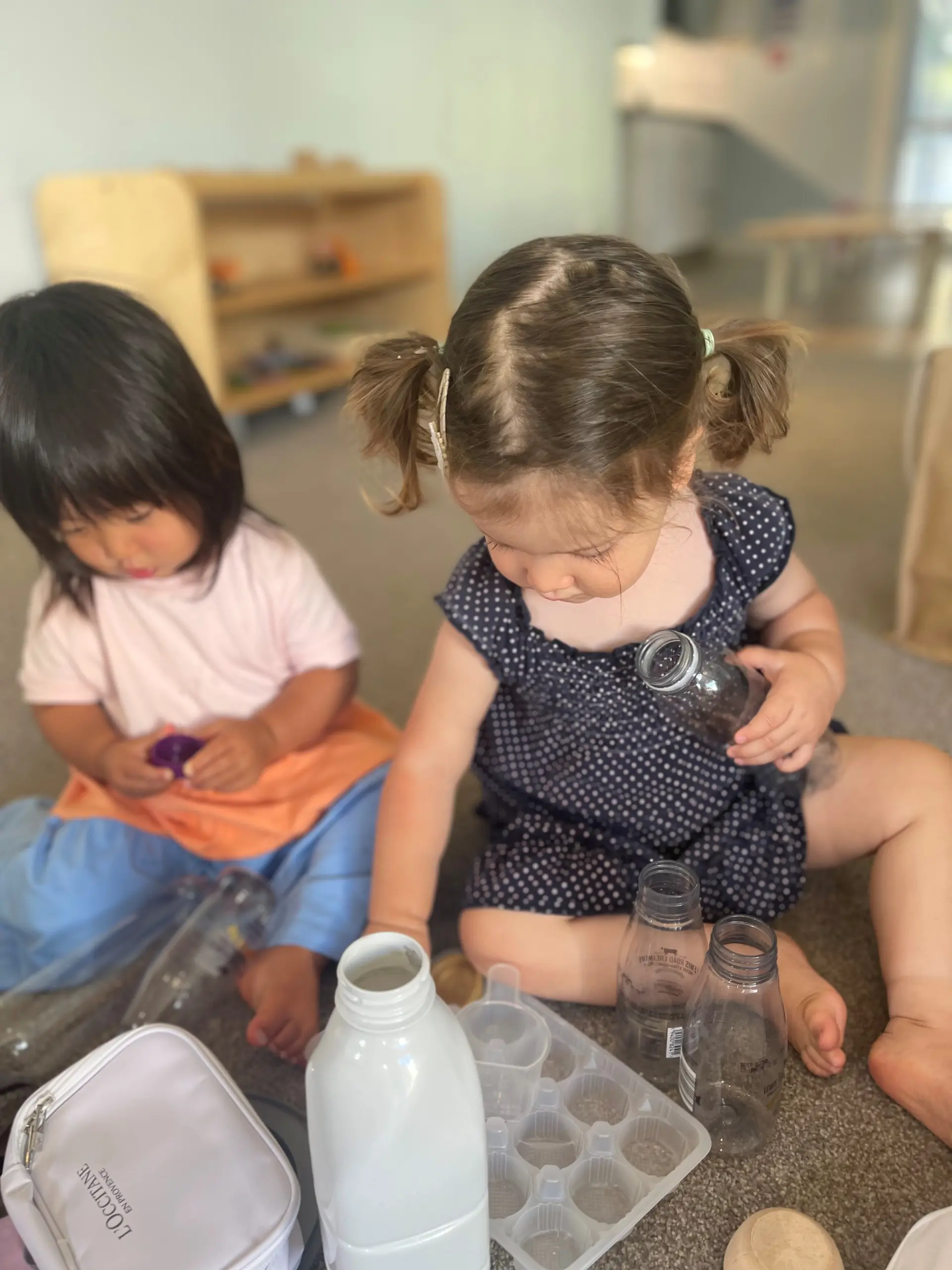 toddler playing with recycle bottles at Bambinom room